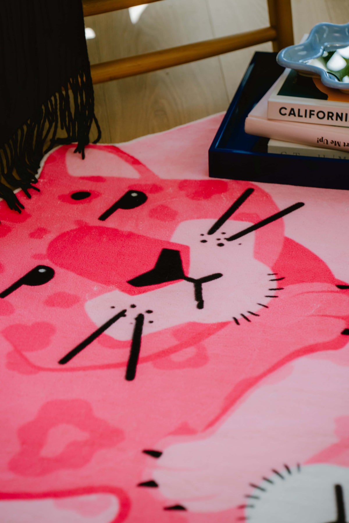 Close-up of the pink panther rug showing detailed face pattern and vibrant color against wooden floor.