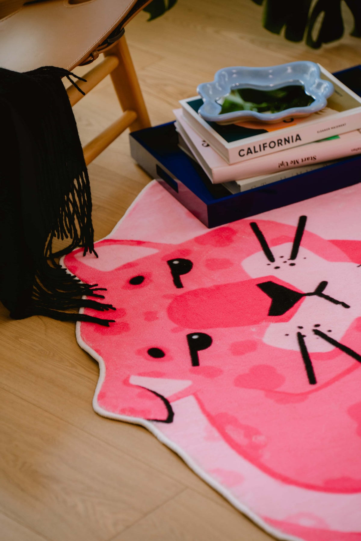Close-up of pink panther rug's face near coffee table books and decor, highlighting its quirky pattern and soft texture.