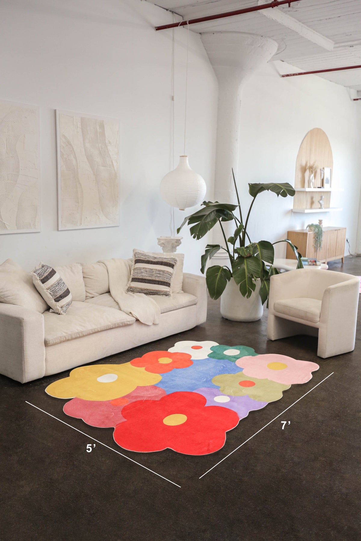 Funky floral rug in a modern loft living room, shown in 5x7 ft size with scalloped edges and vibrant flower shapes.