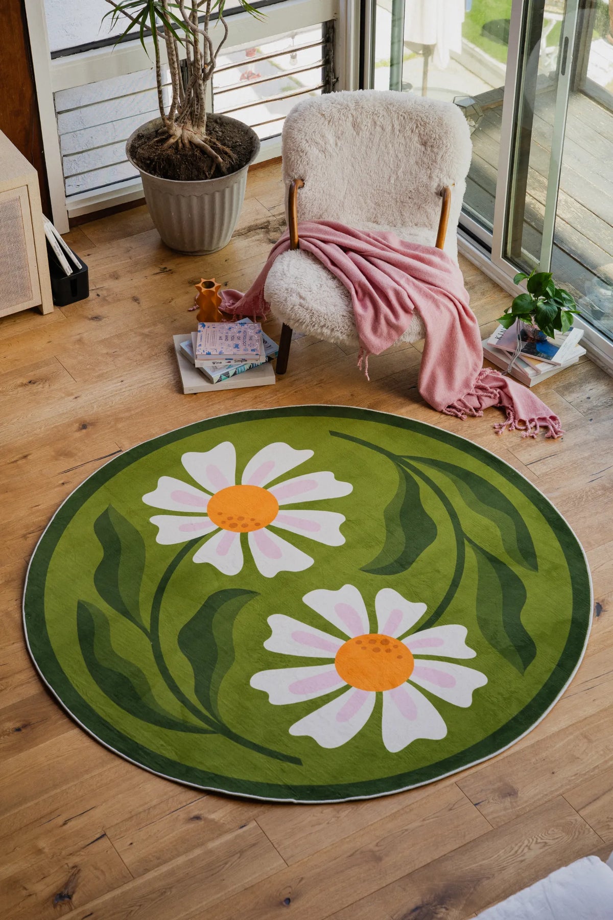 Dual Daisy Round Rug by Jessica Miller styled in a bright living room corner with a cozy armchair and pink throw.