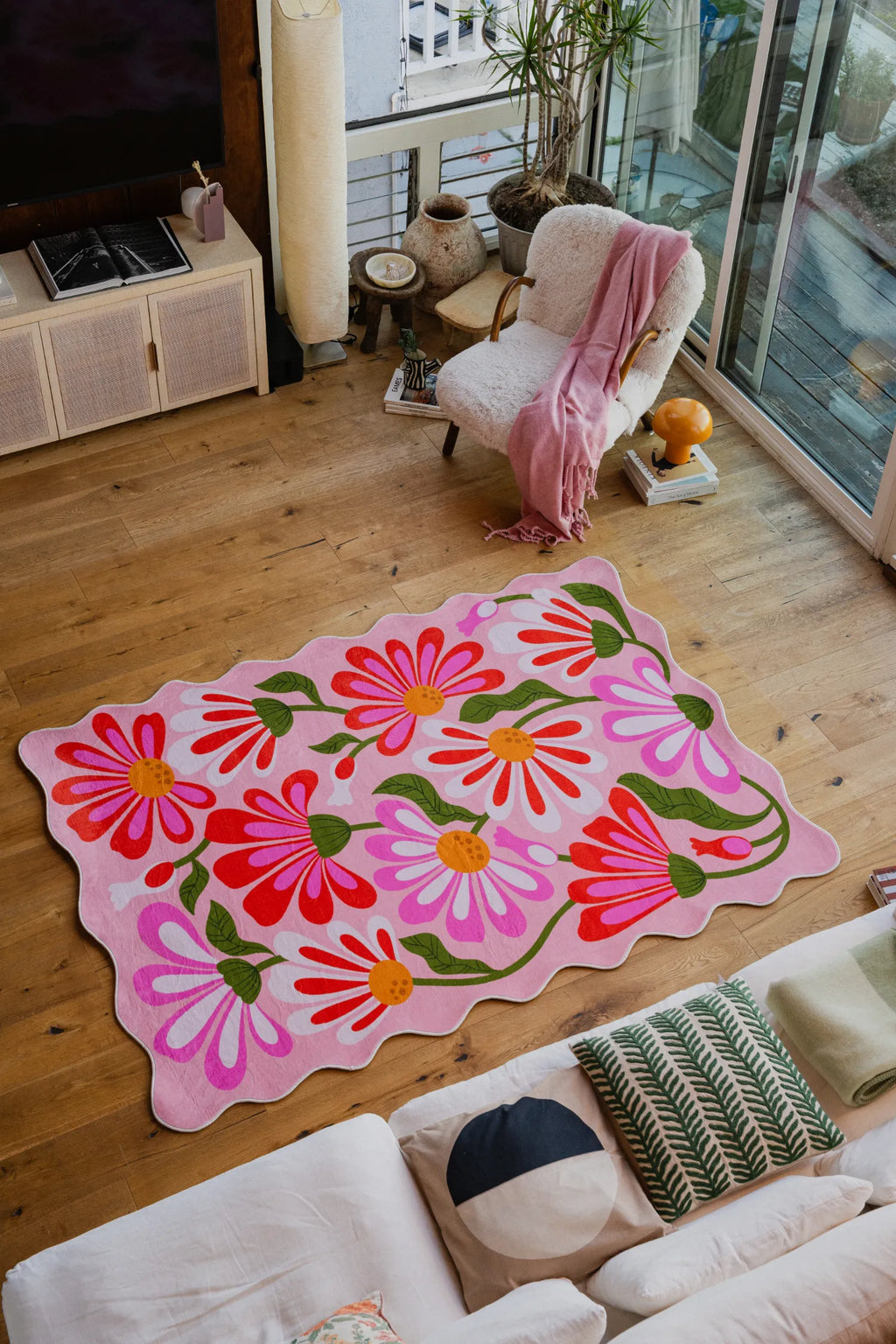 Pink Base Pink Floral Wavy Rug by Jessica Miller placed in a sunlit seating area on wood floor.
