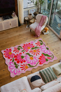 Pink Base Pink Floral Wavy Rug by Jessica Miller placed in a sunlit seating area on wood floor.