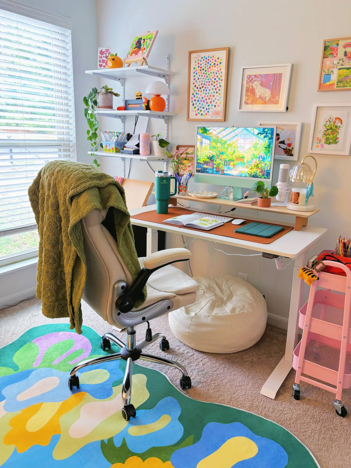 Botanical floral rug placed under a desk chair in a bright home office with wall art, shelves, and soft carpeted floor.